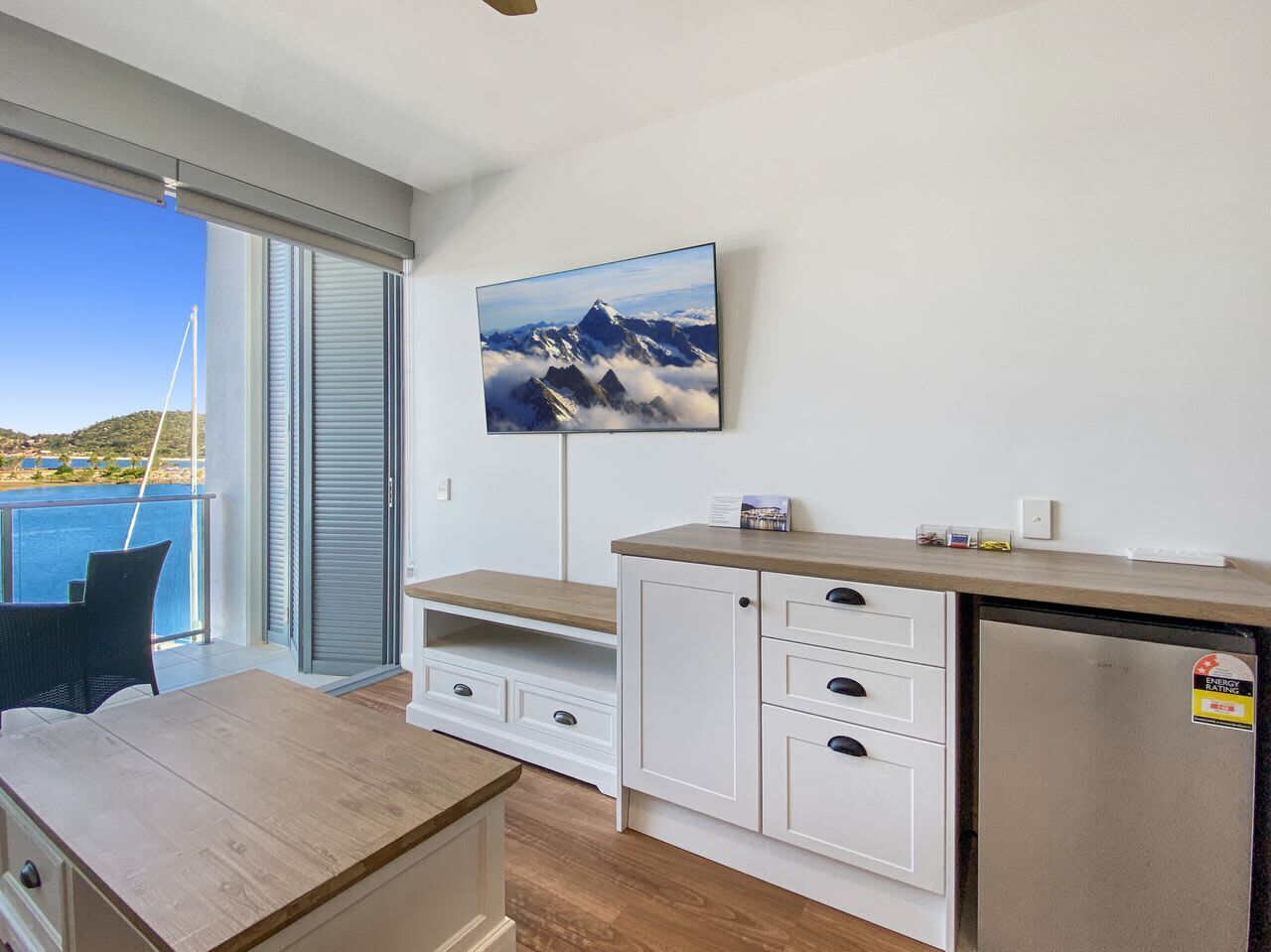 A modern kitchen with a built-in refrigerator, wooden cabinets, and a large window overlooking a scenic view.