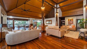 A spacious living area with wooden flooring, a large sofa, a coffee table, and a ceiling fan.