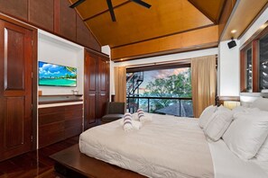 A hotel room with a bed, a TV, a balcony with a view, and wooden paneling.