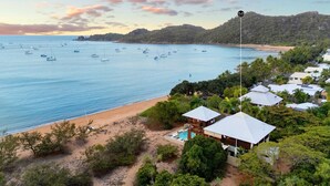 A coastal property with a swimming pool, beach access, and boats in the water.