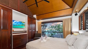 A hotel room with a bed, a TV, a balcony with a view, and wooden paneling.