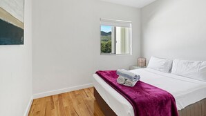 Ein Schlafzimmer mit einem Bett, einem Fenster mit Blick, einem Deckenventilator und Holzboden.