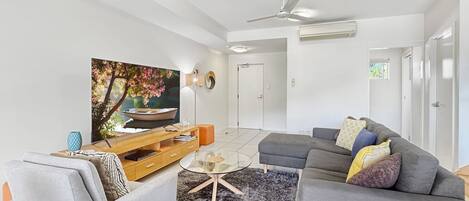A modern living room with a sofa, armchair, coffee table, and a painting on the wall.