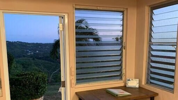 A small room with a sliding glass door leading to a garden, a wooden table, and a bench.