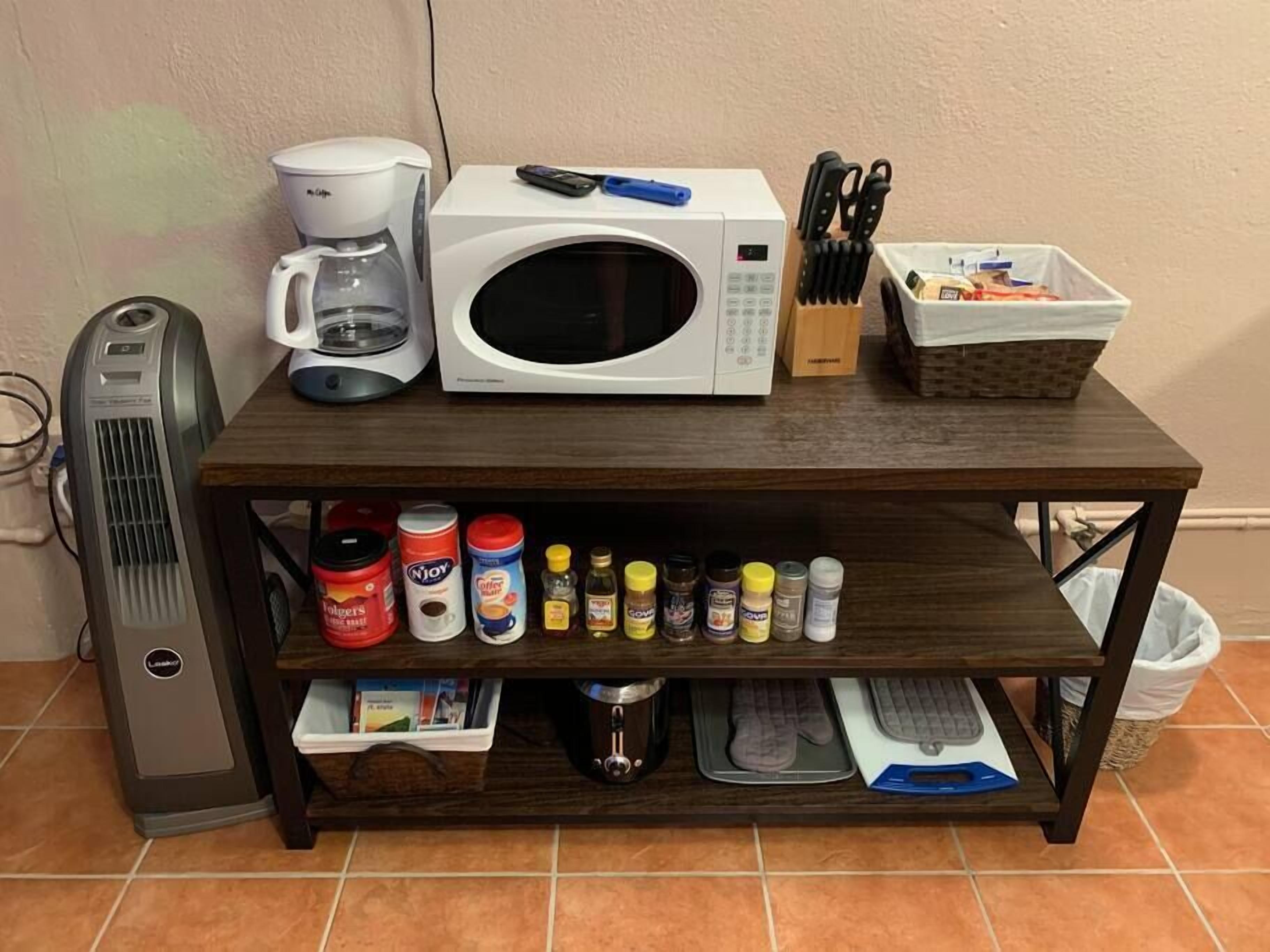A kitchen counter with a microwave, coffee maker, and various kitchen items.