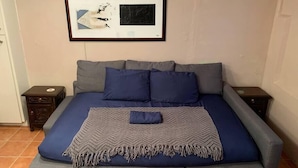 A bed with a blue and gray bedspread, two pillows, and a chevron-patterned throw.