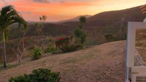 A view from a balcony overlooking a hilly landscape during sunset.