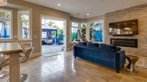 A spacious living room with a large TV, a blue sofa, and a stone fireplace. - FIVE generous bedrooms and a REAL indoor Treehouse for kids  - see our VIDEO!! (Mission Viejo)