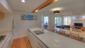 A modern kitchen with a built-in stove, a sink, and a dining area with a table and chairs.