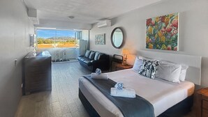 A hotel room with a large bed, a sofa, a desk, and a view of the outdoors.
