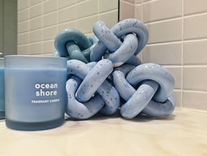 Une bougie bleue avec l’inscription « bord de mer » et un objet bleu en forme de nœud.