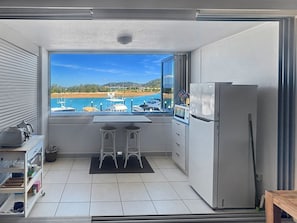 Eine kompakte Küche mit Blick auf eine Marina, inklusive Kühlschrank und einer kleinen Essecke.