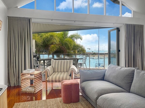 Een moderne woonkamer met een groot raam met uitzicht op een jachthaven en water.