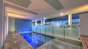 A modern indoor pool area with a clear view of the pool, a metal handrail, and a tiled floor. - Maggies Beachfront Apt. 7 (Horseshoe Bay)