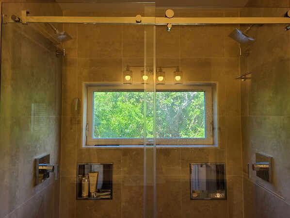 Un baño con un ventanal grande, dos lavamanos y una zona de ducha.