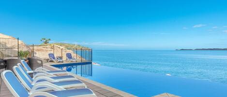 Relax by the ocean with a luxurious infinity pool and comfortable lounge seating.