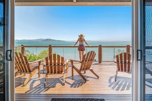 A deck with wooden chairs and a view of the ocean.