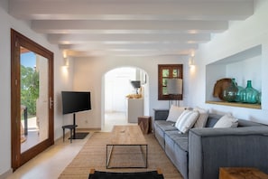 Relax in this stylish living room with a large sofa, flat-screen TV, and access to an outdoor area.