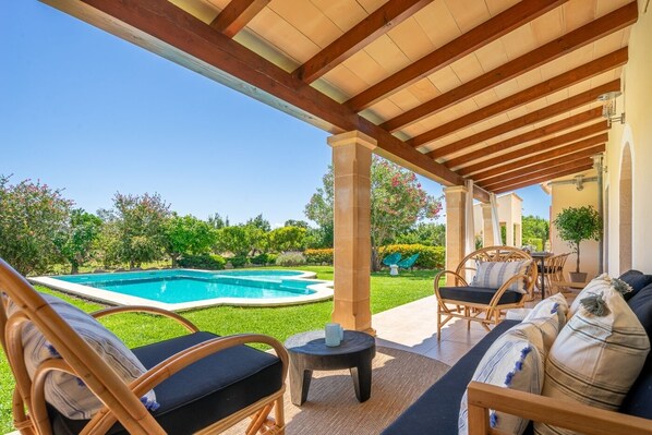 Relax in a serene outdoor space with a pool view, wicker chairs, and a small table.