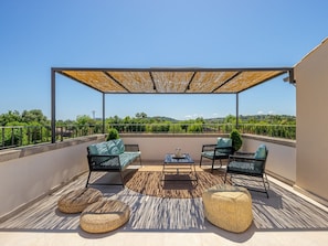Relax on the spacious outdoor terrace with a sofa, chairs, and dining table, taking in the breathtaking views of the surrounding landscape.