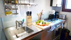 A modern kitchen with stainless steel appliances, a sink, and a countertop with fresh vegetables. - Romantic Attic with Superb View of Madonna del Orto Gothic Church (Venezia)
