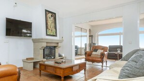 A living room with a fireplace, a television, and a large window offering a view of the outdoors. - Wonderful private villa for 10 people with private pool, WIFI, TV and pets allowed (Lloret De Mar)