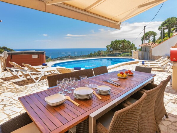 An outdoor dining area with a pool and ocean view.