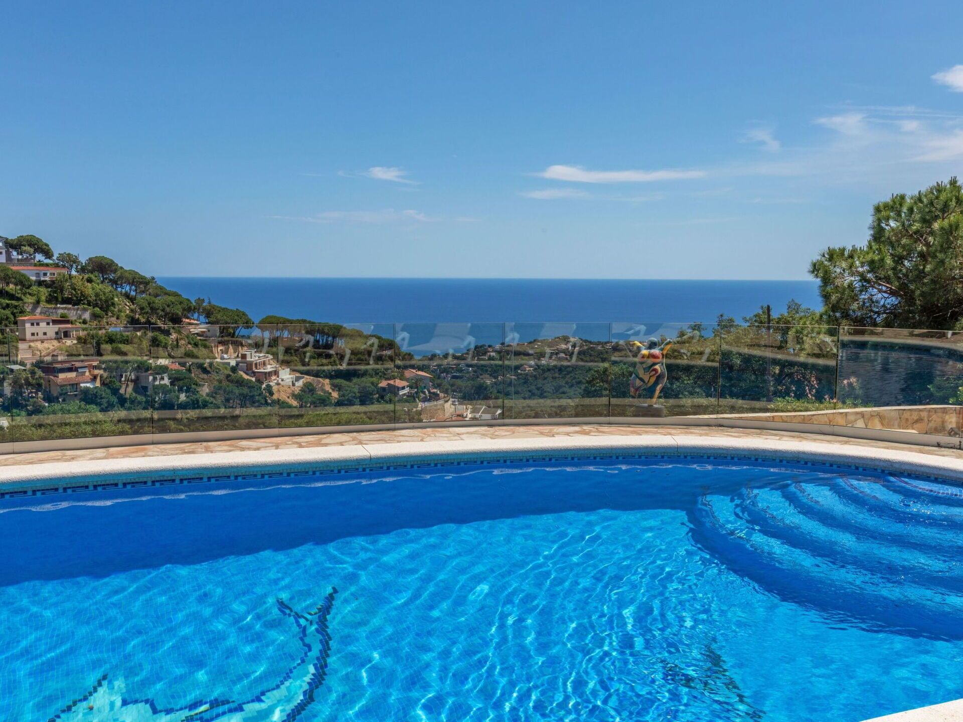 Piscina azul cristalina con vistas al mar y una ladera.