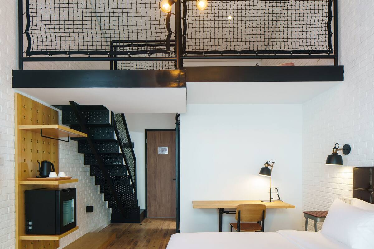 Un dormitorio estilo loft con literas, estanterías de madera, un escritorio y una escalera.
