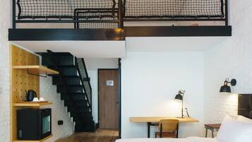 A loft-style bedroom with a bunk bed, wooden shelving, a desk, and a staircase.