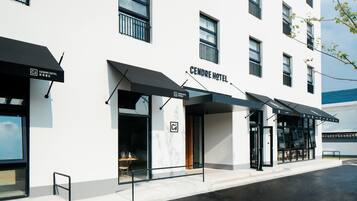 A modern hotel with a white facade, black awnings, and a visible entrance.