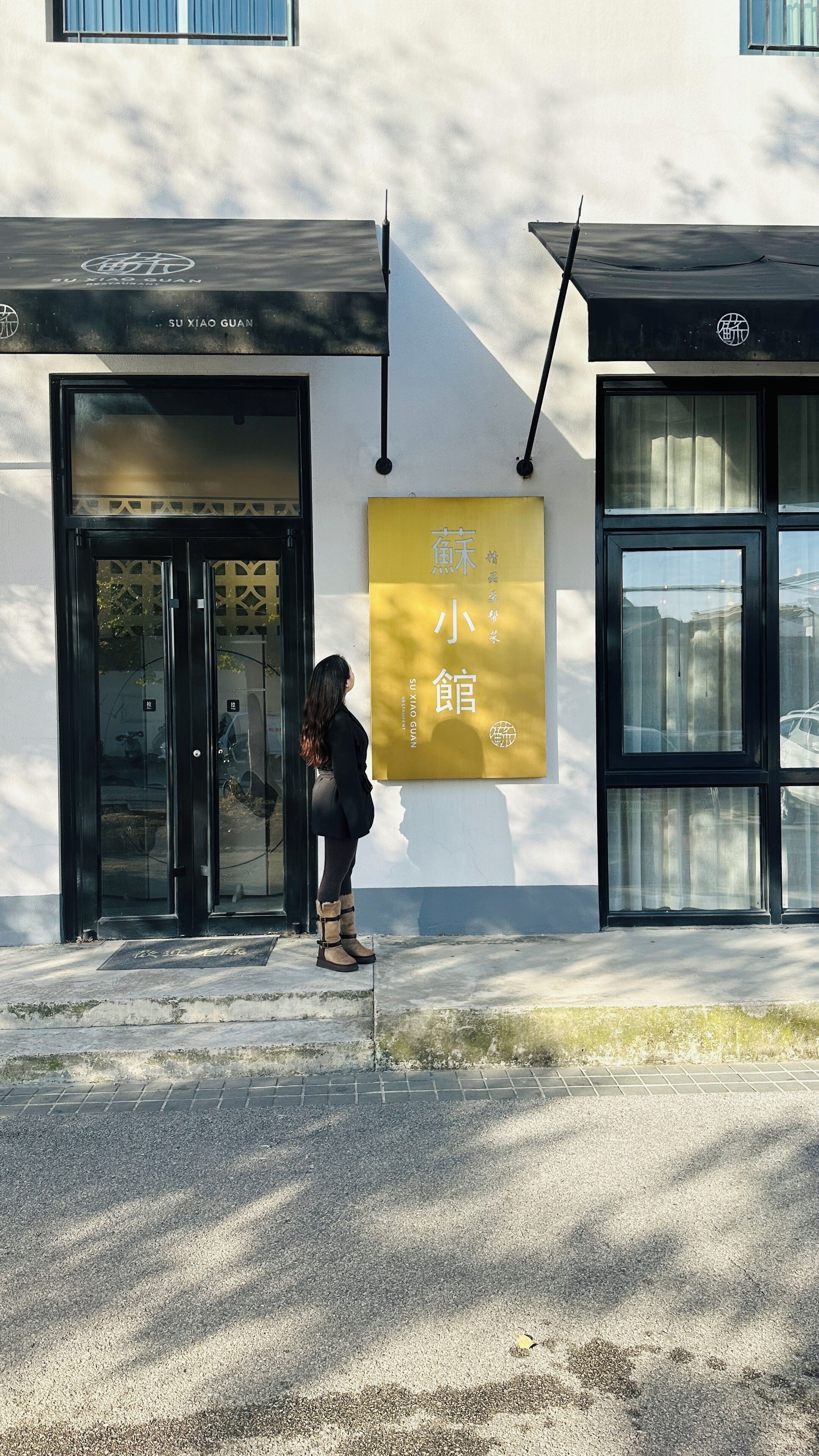 A building with a yellow signboard, a black entrance, and a person standing outside.
