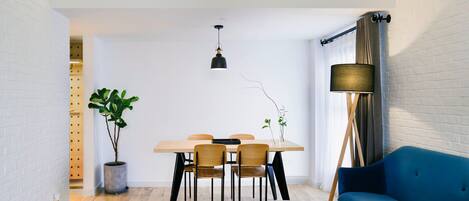 A modern, compact living space with a dining area, a sofa, and a potted plant.