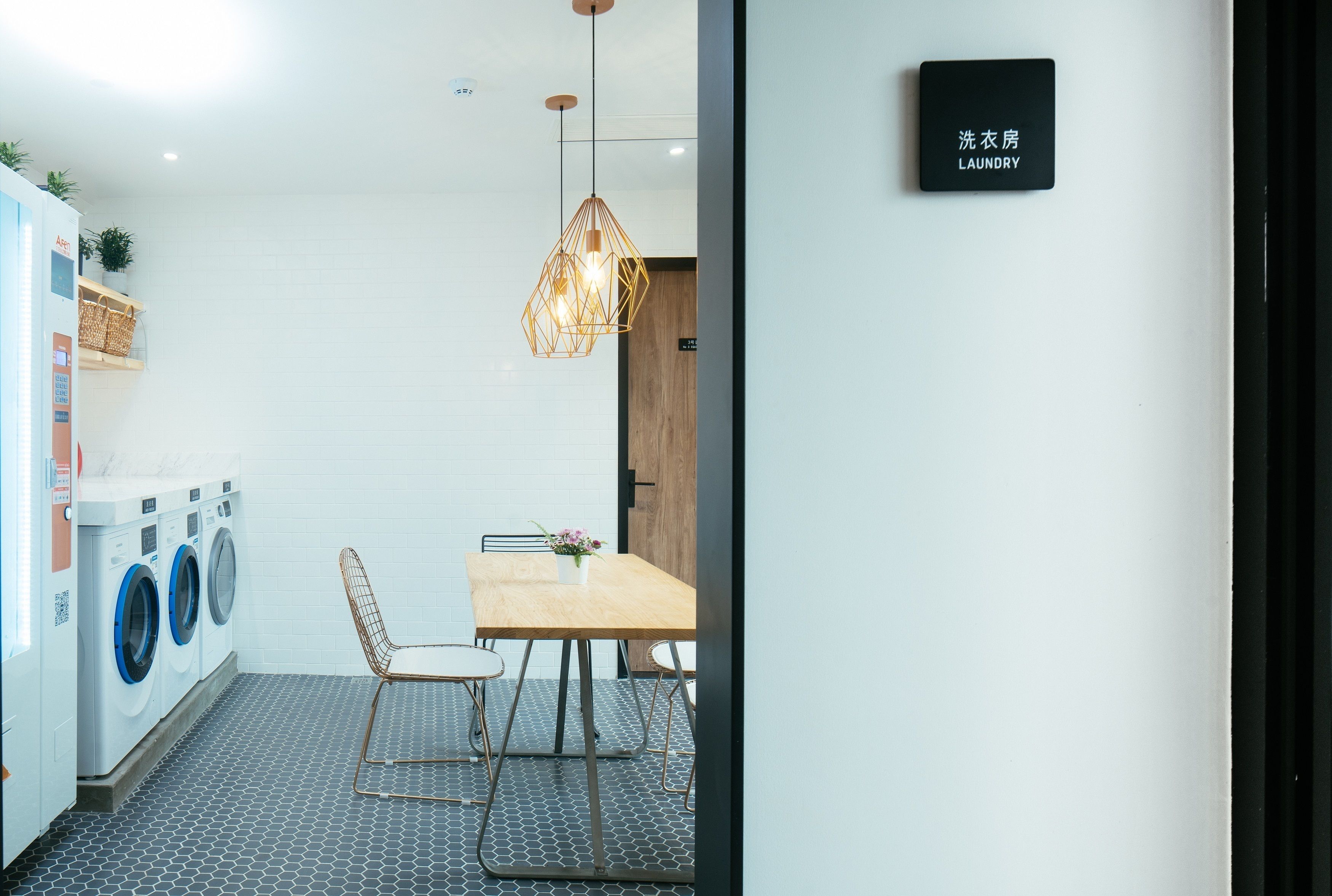 A laundry room with a table and chairs, a hanging light fixture, and a sign indicating the room's purpose.