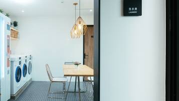 A laundry room with a table and chairs, a hanging light fixture, and a sign indicating the room's purpose.