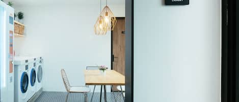 A laundry room with a table and chairs, a hanging light fixture, and a sign indicating the room's purpose.