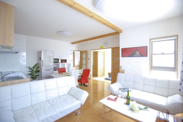 Una sala de estar moderna con sofás blancos, un comedor y una cocina.