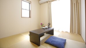 A room with tatami flooring, a low table, a window with a curtain, and an air conditioning unit. - 4-bedrooms 2-toilet 2-bathroom near FushimiInari with free parking (Kyoto)