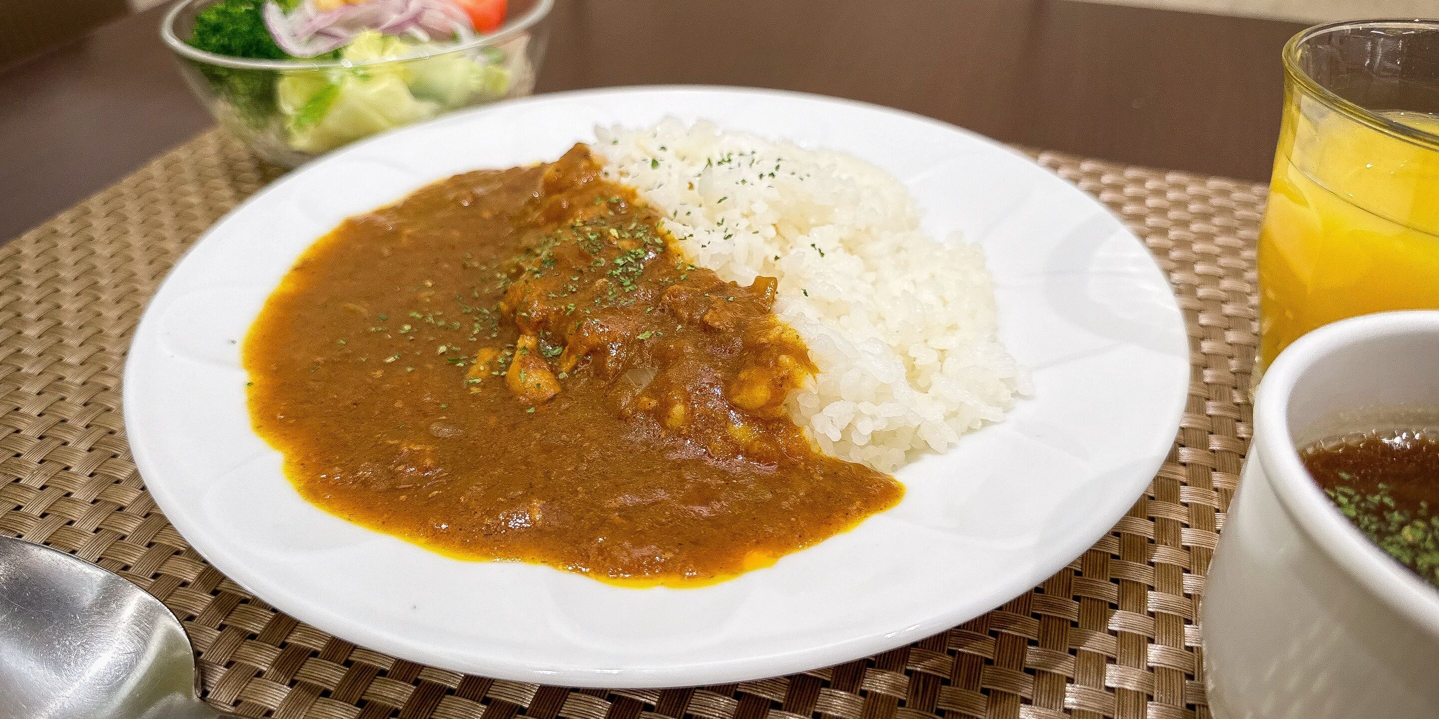 A plate of curry and rice on a woven placemat.