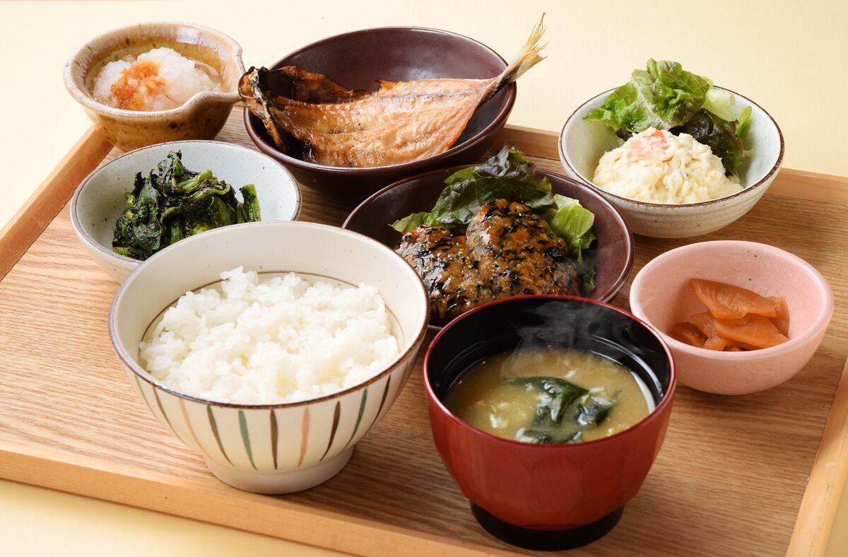 A wooden tray with various bowls of Japanese food, including rice, fish, and soup.