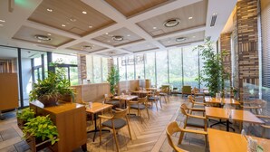 A modern restaurant with wooden furniture, large windows, and potted plants. - Ours Inn Hankyu (Tokyo)