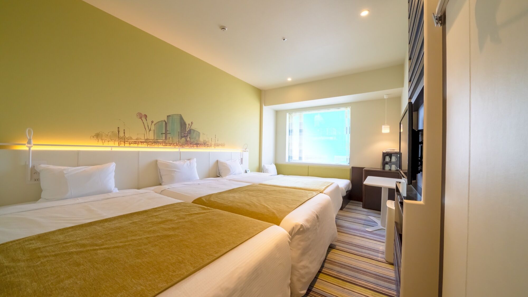 A hotel room with two beds, a desk, a chair, a window with blinds, and a wall-mounted artwork.