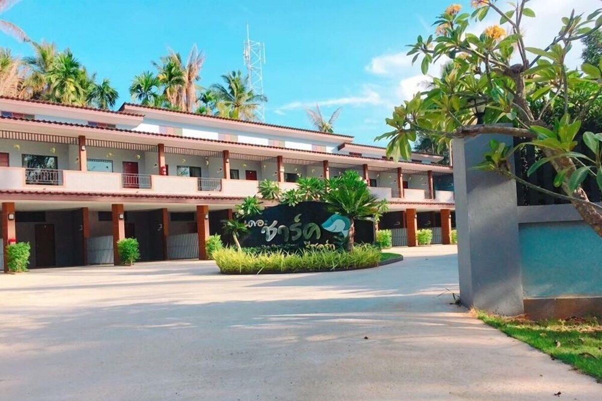 A hotel with a central courtyard, multiple balconies, and a sign with local script.