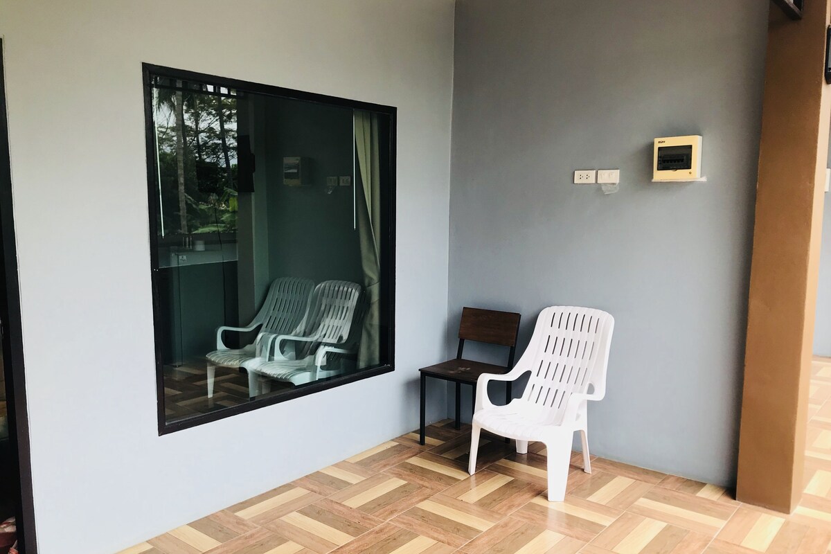 A room with a large window, two chairs, a small table, and a wall-mounted electrical outlet.
