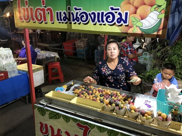 A street food vendor stall with a variety of colorful fruits and a sign in a foreign language.