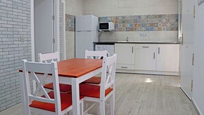 A compact kitchen with white cabinets, a microwave, and a tiled backsplash. - Bungalow with Wi-Fi and shared pool (CONIL DE LA FRONTERA)