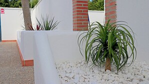 A modern outdoor area with white walls, a brick column, and a plant in a white pot. - Bungalow with Wi-Fi and shared pool (CONIL DE LA FRONTERA)