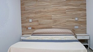 A bedroom with a wooden headboard, a bed with patterned bedding, bedside tables, and a nightstand. - Bungalow with Wi-Fi and shared pool (CONIL DE LA FRONTERA)