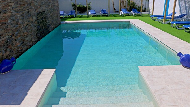 A rectangular swimming pool with clear blue water, surrounded by a stone wall and a tiled deck. - Bungalow with Wi-Fi and shared pool (CONIL DE LA FRONTERA)