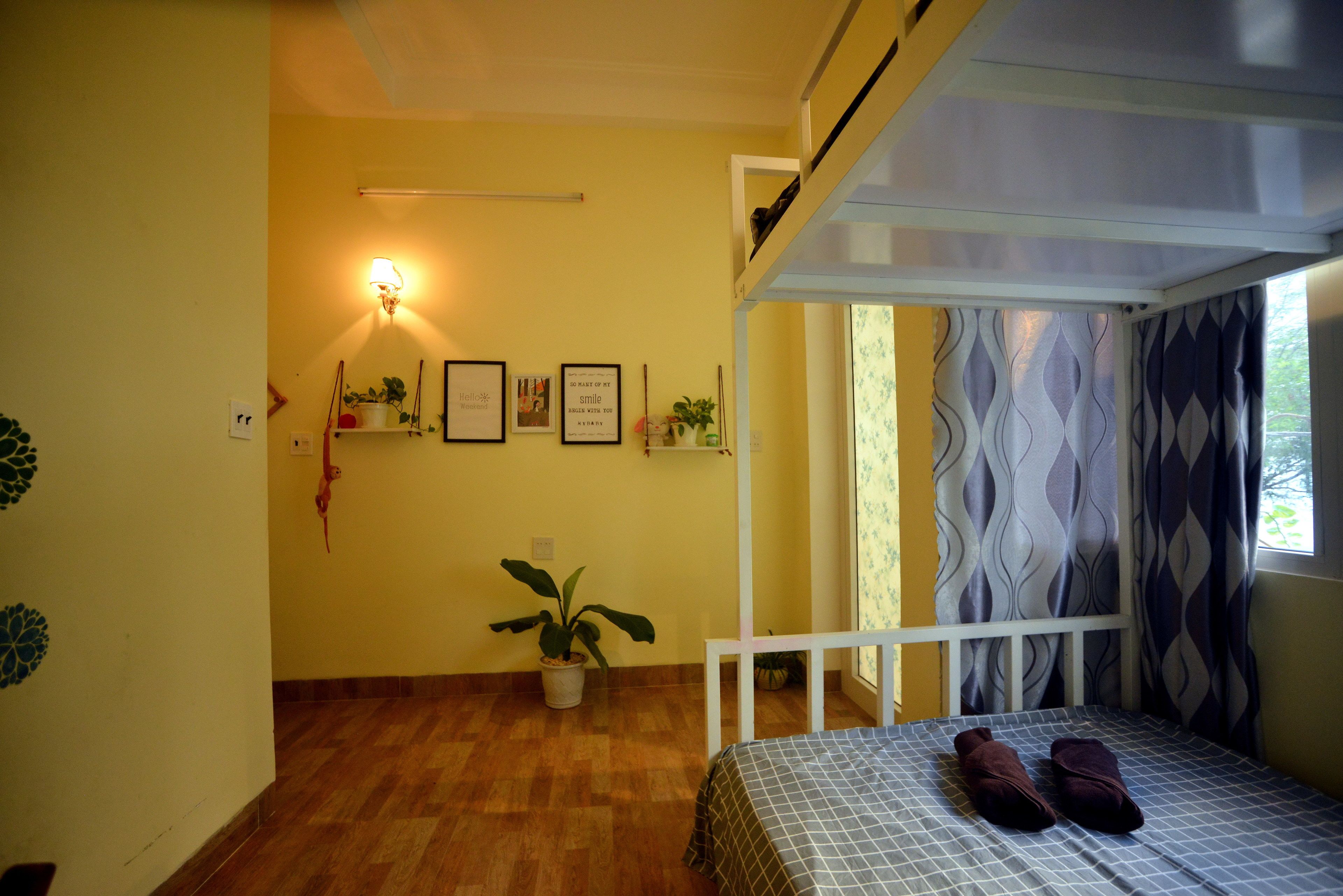 Un dormitorio con cama, una planta en maceta, estantes en la pared y una ventana con cortinas.